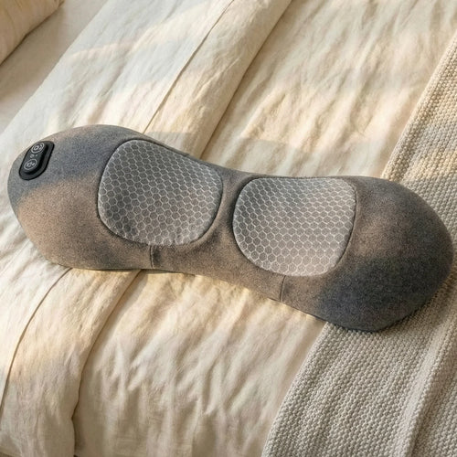 Gray heated neck massager pillow with control buttons on a bed